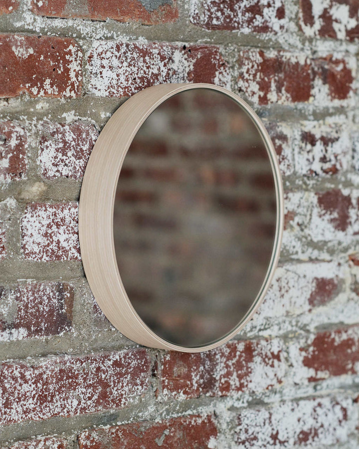 White Oak Wood Round Mirror by Saito Wood Co for Nalata Nalata hanging against exposed brick wall