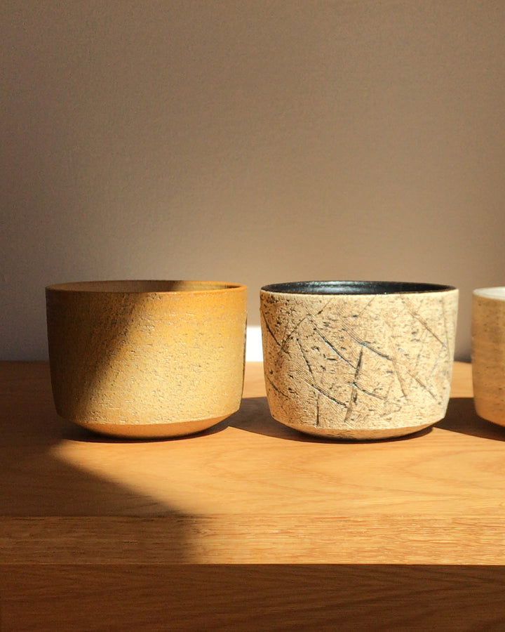 In-situation image of the kuro black matcha bowl next to otosai yellow matcha bowl. 